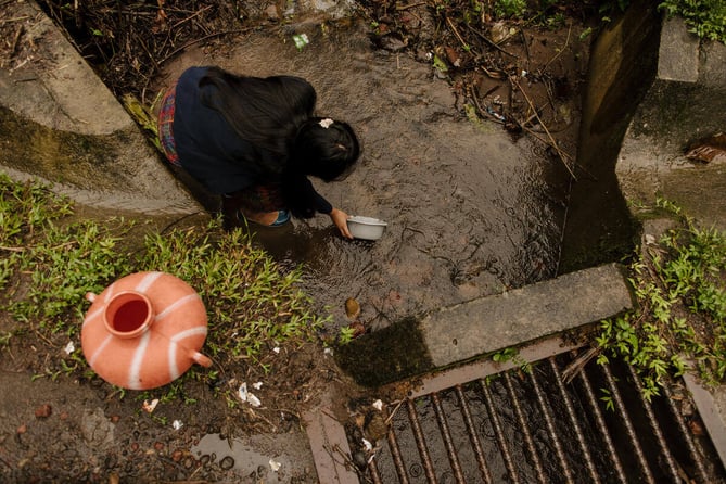 Niña recoge agua contaminada 